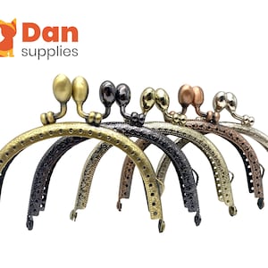 May include: A collection of seven metal purse frames in various finishes, including antique brass, black, and copper. Each frame has a decorative arched design with a clasp at the top and holes for sewing. The Dan Supplies logo is in the upper left corner.