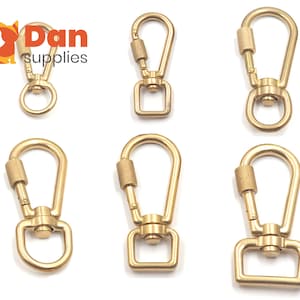 May include: Six gold-toned metal swivel snap hooks with a spring-loaded gate. The hooks have a D-ring on one end and a swiveling loop on the other end. The hooks are arranged in two rows of three.