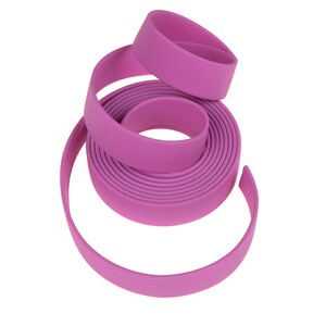 May include: A roll of pink, flat, flexible webbing. The webbing is rolled up and the end is curled around the roll.