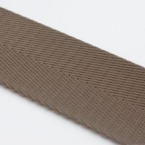 May include: A close-up of brown woven ribbon with a herringbone pattern.