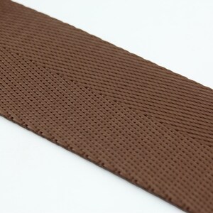 May include: Brown woven ribbon with a herringbone pattern.