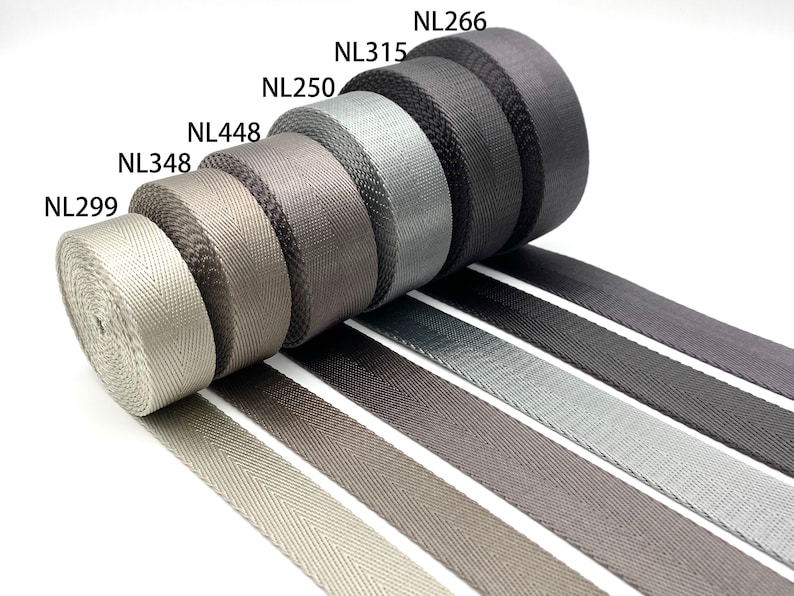 May include: A variety of gray, black, and silver woven webbing rolls with the product codes NL299, NL348, NL448, NL250, NL315, and NL266.