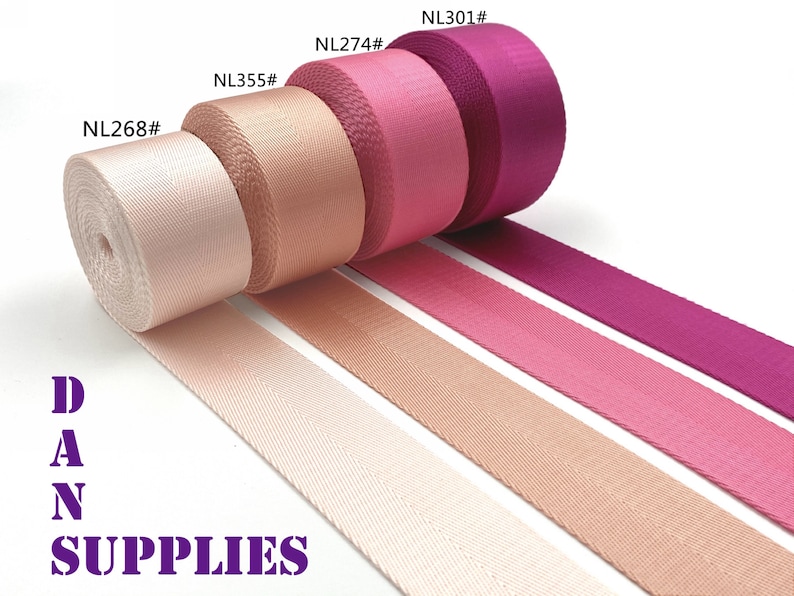 May include: Assortment of colorful rolls of webbing in shades of pink and purple. The rolls are labeled with numbers, and the text "DAN SUPPLIES" is visible in purple. The webbing is displayed on a white background.