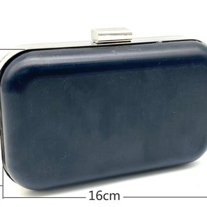 May include: A black clutch purse with a silver metal frame and clasp. The purse measures 9.5 inches by 16 inches.