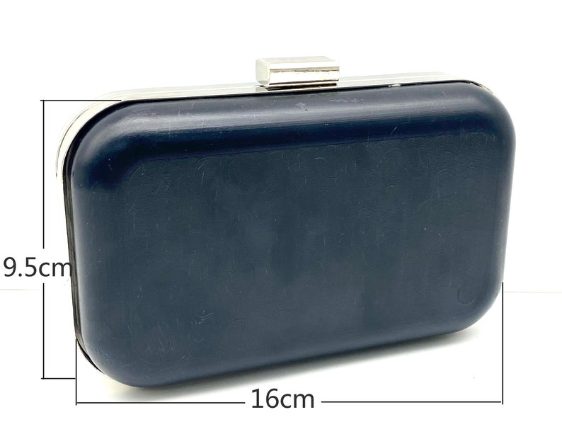 May include: A black clutch purse with a silver metal frame and clasp. The purse measures 9.5 inches by 16 inches.