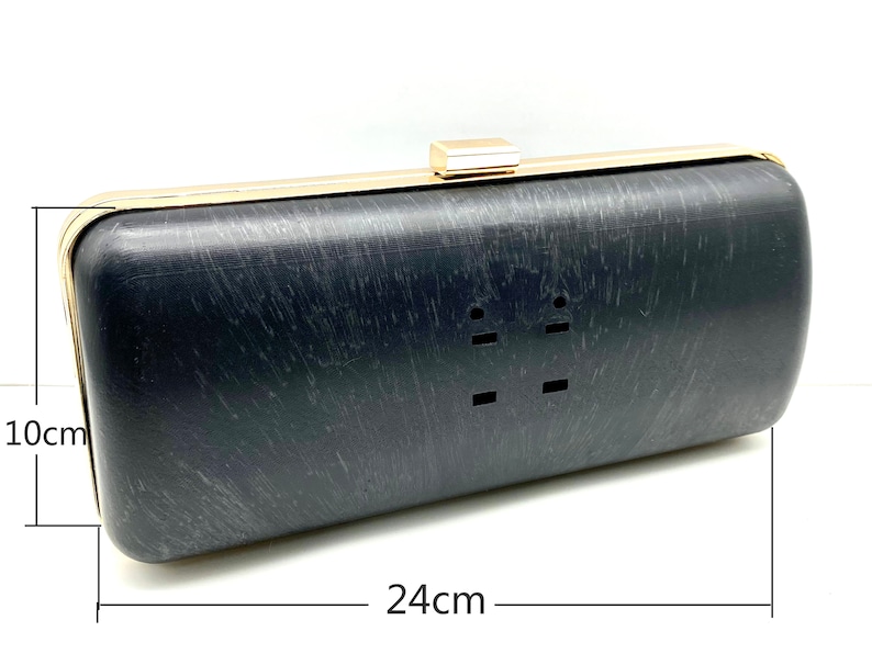 Pu&ograve; includere: Una pochette nera con cornice e chiusura in metallo dorato. La pochette misura 24 cm di lunghezza e 10 cm di altezza.