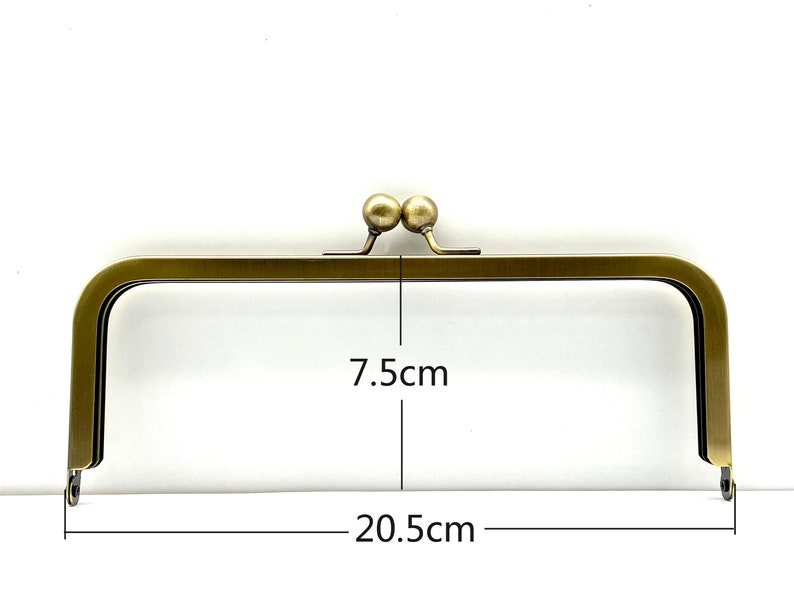 May include: A gold-toned metal purse frame with two round knobs at the top. The frame measures 7.5 inches by 20.5 inches.