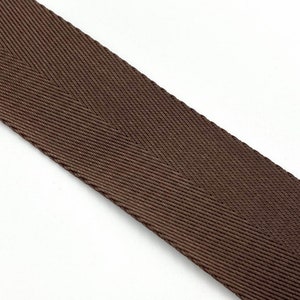 May include: A close-up of brown woven webbing with a herringbone pattern.