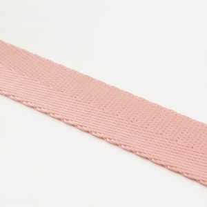 May include: A close-up of a length of pink woven fabric, likely a ribbon or strap, against a white background. The fabric has a diagonal weave pattern and a slightly textured surface. The color is a soft, muted pink.