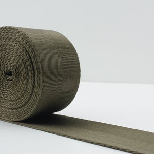 May include: A roll of olive green webbing, a type of heavy-duty fabric used for straps and belts.