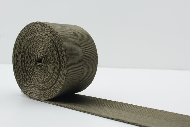 May include: A roll of olive green webbing, a type of heavy-duty fabric used for straps and belts.
