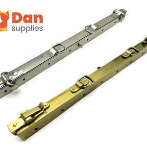 Può includere: Due pezzi di ferramenta per telaio di borsa a mano in metallo. Uno è argentato e l'altro è dorato. Entrambi hanno più fori e una fibbia scorrevole.