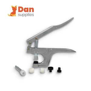 May include: A silver metal snap fastener pliers tool with a spring-loaded handle mechanism. The set includes a metal rod with a white plastic tip, two white cylindrical plastic pieces, and two small black plastic components for attaching snaps.