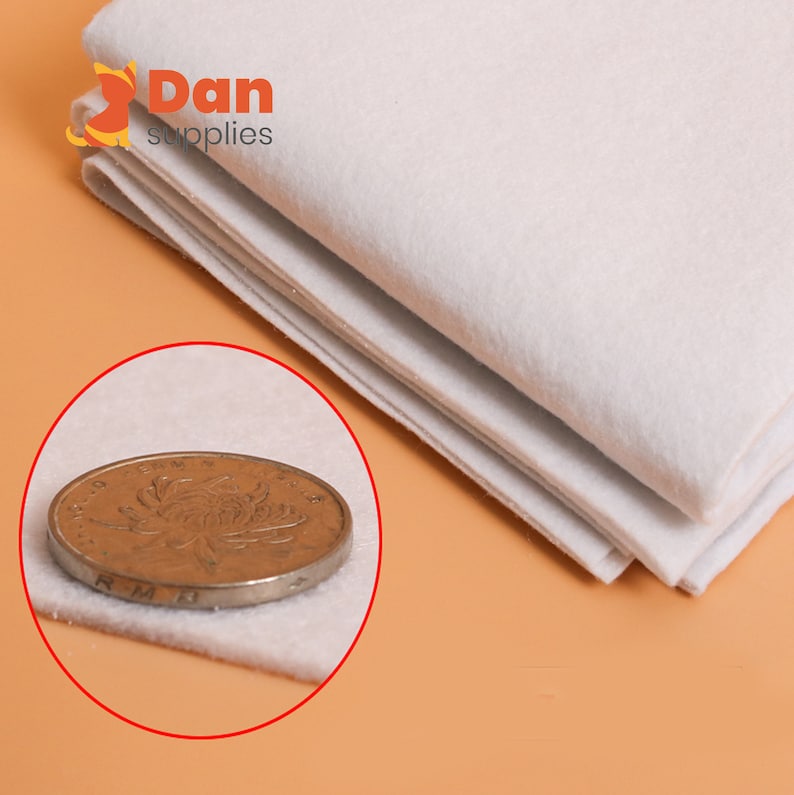 May include: A white felt fabric sheet folded in thirds. A Canadian one dollar coin is placed on top of the fabric to show the thickness.