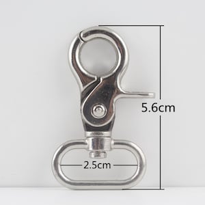 Op de afbeelding: Een zilverkleurige metalen draaihaak met een veergrendel. De haak is 5,6 cm lang en 2,5 cm breed. Hij is ontworpen om aan een riem of ander item te bevestigen. De haak is gemaakt van duurzaam metaal.