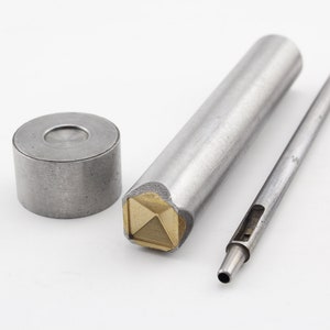 May include: A set of three metal tools for leather crafting. The tools include a round punch, a square punch with a pyramid-shaped tip, and a long, thin tool with a hole at the end.