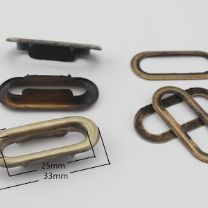 Op de afbeelding: Vier ovale metalen oogjes in antiek goud met verschillende maten. Het grootste oogje meet 25 mm bij 33 mm. Het kleinste oogje meet 7 mm bij 15 mm.