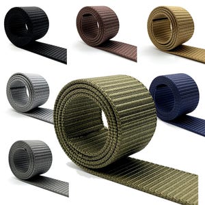 Pode incluir: Uma coleção de correias de nylon em várias cores: preto, castanho, bege, cinzento, verde-oliva e azul marinho. Cada rolo é enrolado, com uma secção desenrolada para mostrar a textura canelada. Adequado para artesanato ou equipamentos para exteriores.