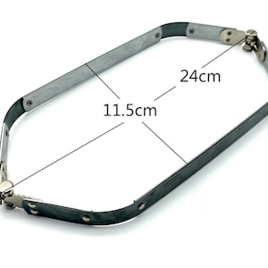 Könnte beinhalten: Ein silberfarbenes Metall- und schwarzes Gummiband mit Scharnierdesign. Das Band ist 24 cm lang und 11,5 cm breit. Das Band ist verstellbar.