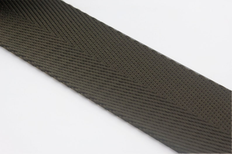 May include: A close-up of a dark green woven webbing strap with a herringbone pattern.