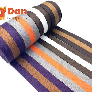 May include: A roll of striped webbing in five different colour combinations. The colours are purple, brown, orange, grey, and white. The webbing is 2 inches wide.