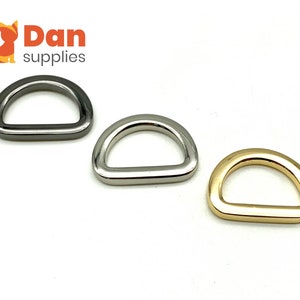 May include: Three D-rings in different finishes: silver, nickel, and gold. The D-rings are a common hardware finding used in crafting and jewelry making.