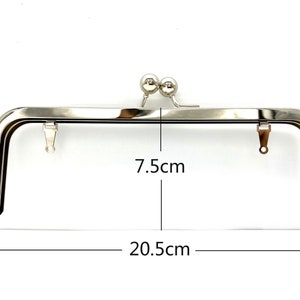 May include: Silver-toned metal purse frame with two round metal clasps. The frame measures 7.5 inches wide and 20.5 inches long.