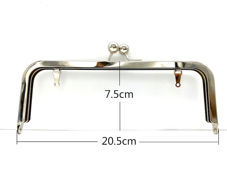 May include: Silver-toned metal purse frame with two round metal clasps. The frame measures 7.5 inches wide and 20.5 inches long.