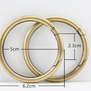 以下が含まれることがあります： スナップ留め具付きのゴールドトーンの金属製キーリング2個。大きなリングの直径は5cm、小さなリングの直径は2.3cmです。