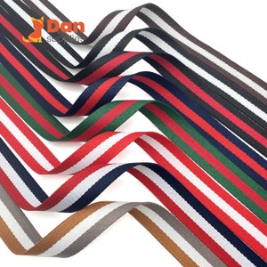 May include: Assortment of striped ribbon in various colors, including red, white, green, blue, and brown. The ribbon is woven with a subtle texture.