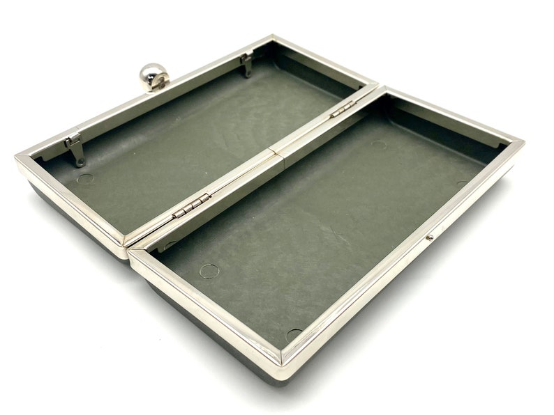 May include: An empty, open, gray, rectangular box with a silver metal frame and hinge. The box has a small silver knob on the top.