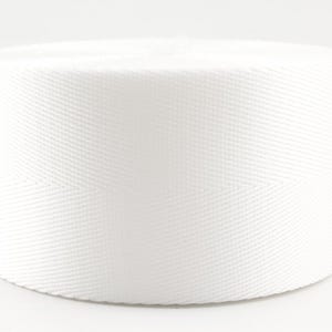 Pode incluir: Um rolo de fita de algod&atilde;o branco, um tipo de tecido forte e tecido que &eacute; frequentemente usado para correias, cintos e outras aplica&ccedil;&otilde;es.