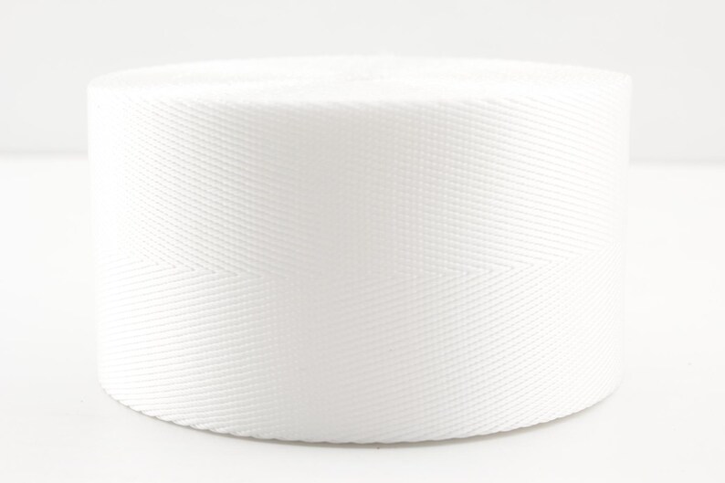 Pode incluir: Um rolo de fita de algod&atilde;o branco, um tipo de tecido forte e tecido que &eacute; frequentemente usado para correias, cintos e outras aplica&ccedil;&otilde;es.