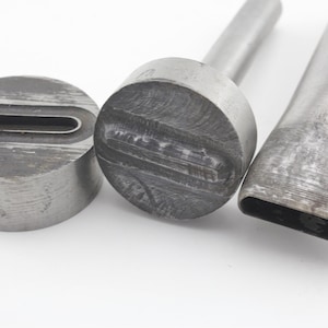 Op de afbeelding: Drie metalen lederen ponsen met verschillende vormen. De ponsen zijn gemaakt van zilverkleurig metaal en hebben een versleten uiterlijk.