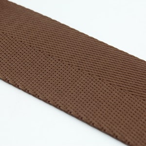 May include: Brown woven ribbon with a herringbone pattern.