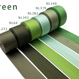 May include: Six rolls of woven nylon webbing in various shades of green, labeled NL233, NL64, NL393, NL382, NL379, and NL340. The fabric strips are arranged in a row, displaying a gradient from dark olive to light mint and bright grass green.