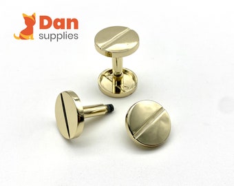 May include: Three gold-colored metal screw-on studs with a single groove on the top. The studs are round and have a flat base.
