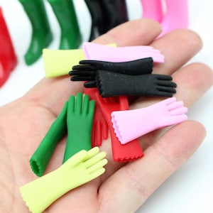 Puede incluir: Una colección de guantes de goma de colores en varios tamaños y estilos, incluyendo verde, rojo, rosa, negro y amarillo. Los guantes están dispuestos en una mano, mostrando sus diferentes diseños y texturas.