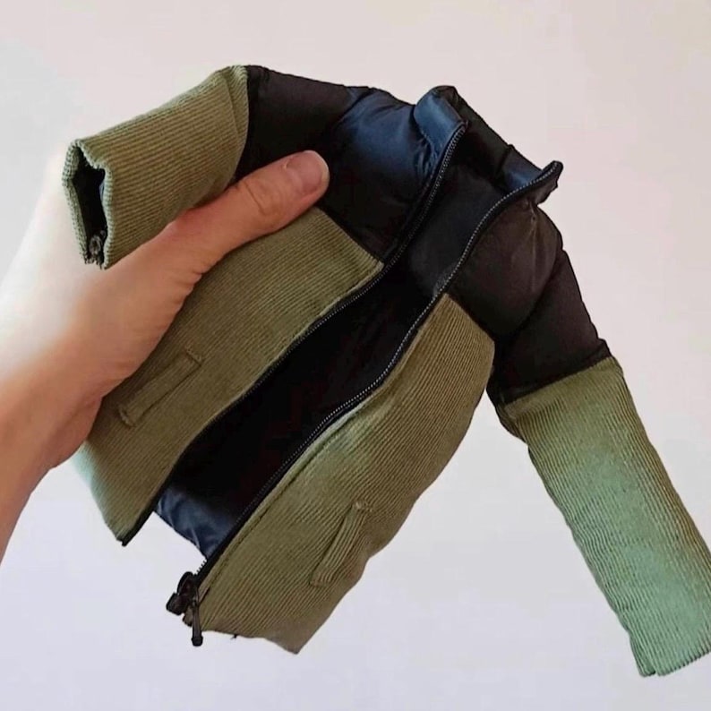 Pode incluir: Uma jaqueta puffer verde e preta com fecho de correr. A jaqueta &eacute; feita de tecido acolchoado e tem gola e punhos canelados.