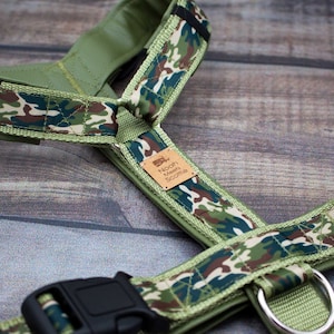 Puede incluir: Arnés para perro de camuflaje verde con hebillas negras y un parche de cuero marrón que dice "Noah's New Scoottie".