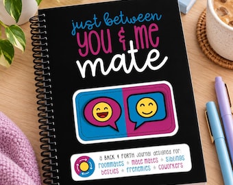 Puede incluir: Un diario de espiral negro con el texto "just between you & me mate" en azul, rosa y blanco. Presenta un gráfico de dos burbujas de diálogo con caras sonrientes amarillas y una etiqueta que enumera "roommates, mate mates, siblings, besties, frenemies, coworkers."