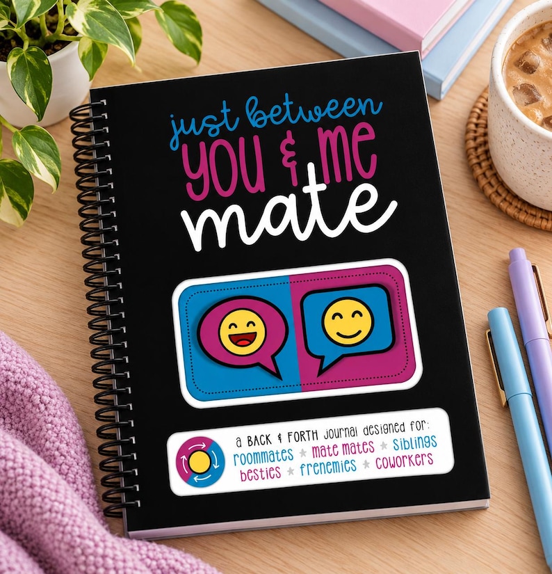 Puede incluir: Un diario de espiral negro con el texto "just between you & me mate" en azul, rosa y blanco. Presenta un gr&aacute;fico de dos burbujas de di&aacute;logo con caras sonrientes amarillas y una etiqueta que enumera "roommates, mate mates, siblings, besties, frenemies, coworkers."
