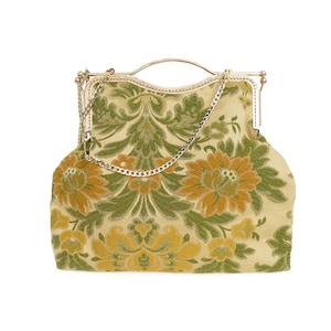 Może przedstawiać: Torebka typu kopertówka w stylu vintage z łańcuszkiem w kolorze złotym i kwiatowym wzorem w odcieniach zieleni i żółci.