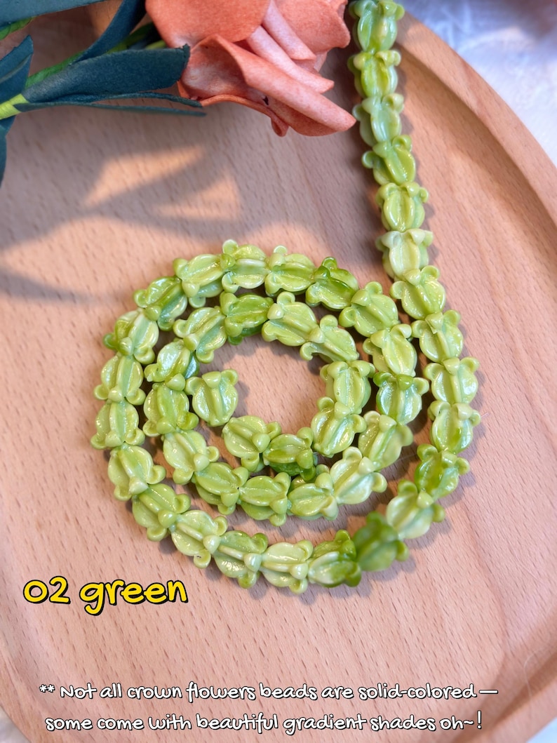 May include: A necklace made of light green flower-shaped beads. The beads are arranged in a circular pattern. The text "02 green" is in the lower left corner. The text below reads "Not all crown flowers beads are solid-colored - some come with beautiful gradient shades oh~!"