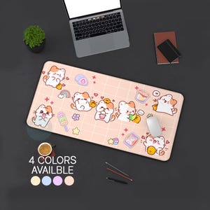 May include: A rectangular pink mousepad featuring a grid pattern and cartoon cat illustrations with food and rainbow graphics. The mousepad has the text "4 COLORS AVAILABLE" with color swatches. A laptop, mouse, and other desk items are visible.