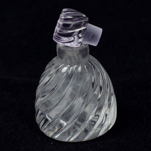 May include: A clear glass bottle with a swirl design and a purple glass stopper.
