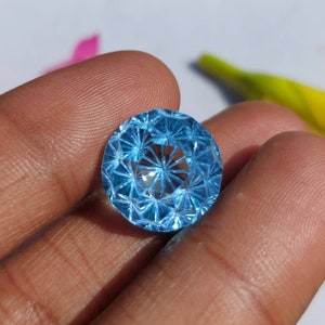 May include: A round, faceted, light blue gemstone with a starburst pattern.