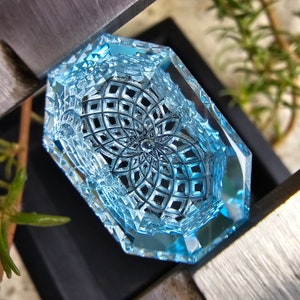 May include: A blue glass paperweight with a geometric design. The design is a repeating pattern of squares and circles.
