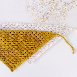 Könnte beinhalten: Ein gelber Dreieckschal aus Häkelarbeit mit einem darüberliegenden weißen Dreieckschal aus Häkelarbeit.