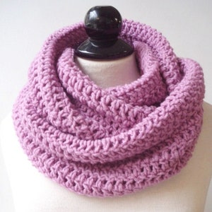 May include: A soft, purple knitted infinity scarf. The scarf is made of a chunky yarn and has a simple, textured stitch pattern.